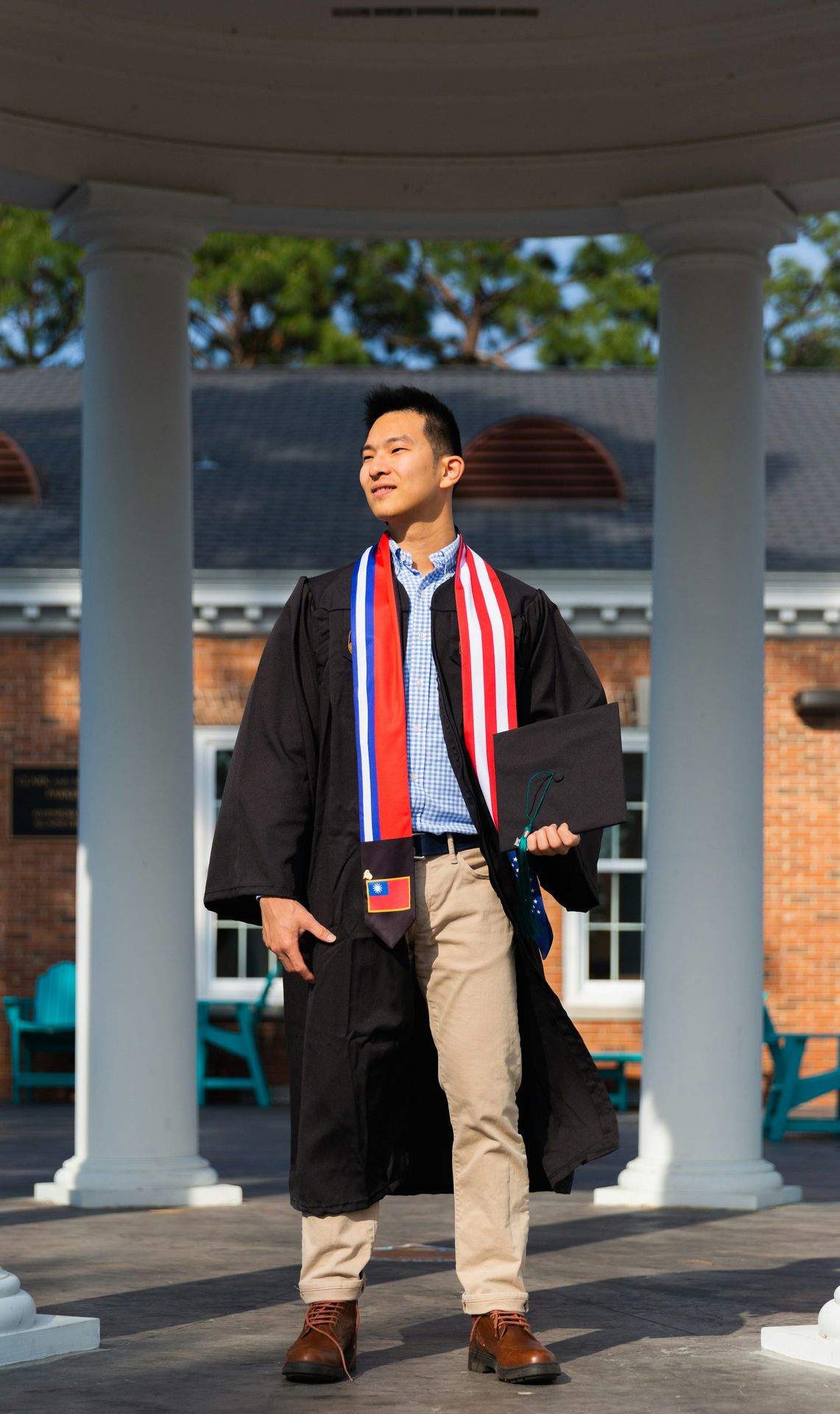 a man in a graduation gown standing under a gazebo